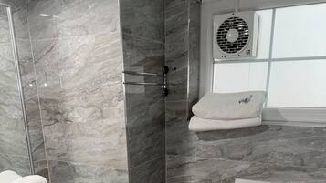 A modern bathroom with a glass shower enclosure, a white sink, a toilet, and a towel rack.