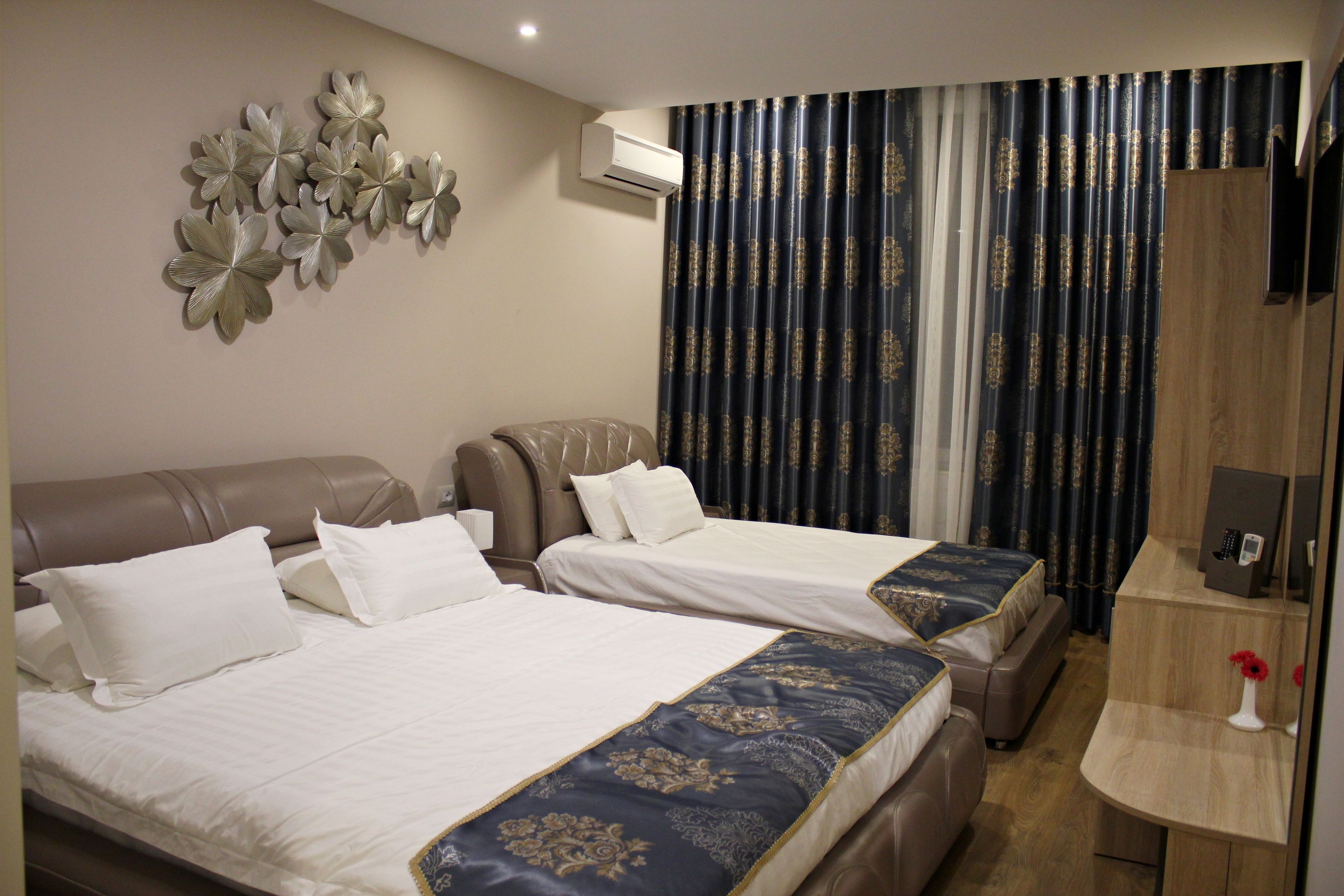 Habitación de hotel con dos camas, un sofá, una mesita y un adorno en la pared.