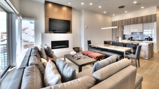 Una sala de estar moderna con un sofá, una mesa de centro y un televisor montado en la pared.