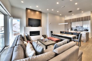 Una sala de estar moderna con un sofá, una mesa de centro y un televisor montado en la pared.