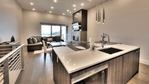 Una cocina moderna con una isla grande, electrodomésticos integrados y un comedor con sofá y sillas.