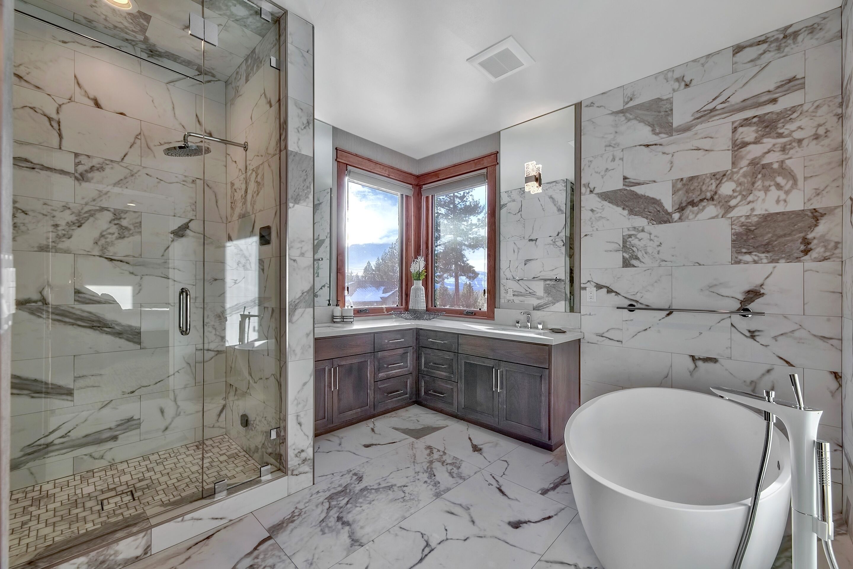 A modern bathroom with a glass-enclosed shower, a freestanding bathtub, and a large mirror.