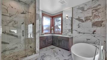 A modern bathroom with a glass-enclosed shower, a freestanding bathtub, and a large mirror.