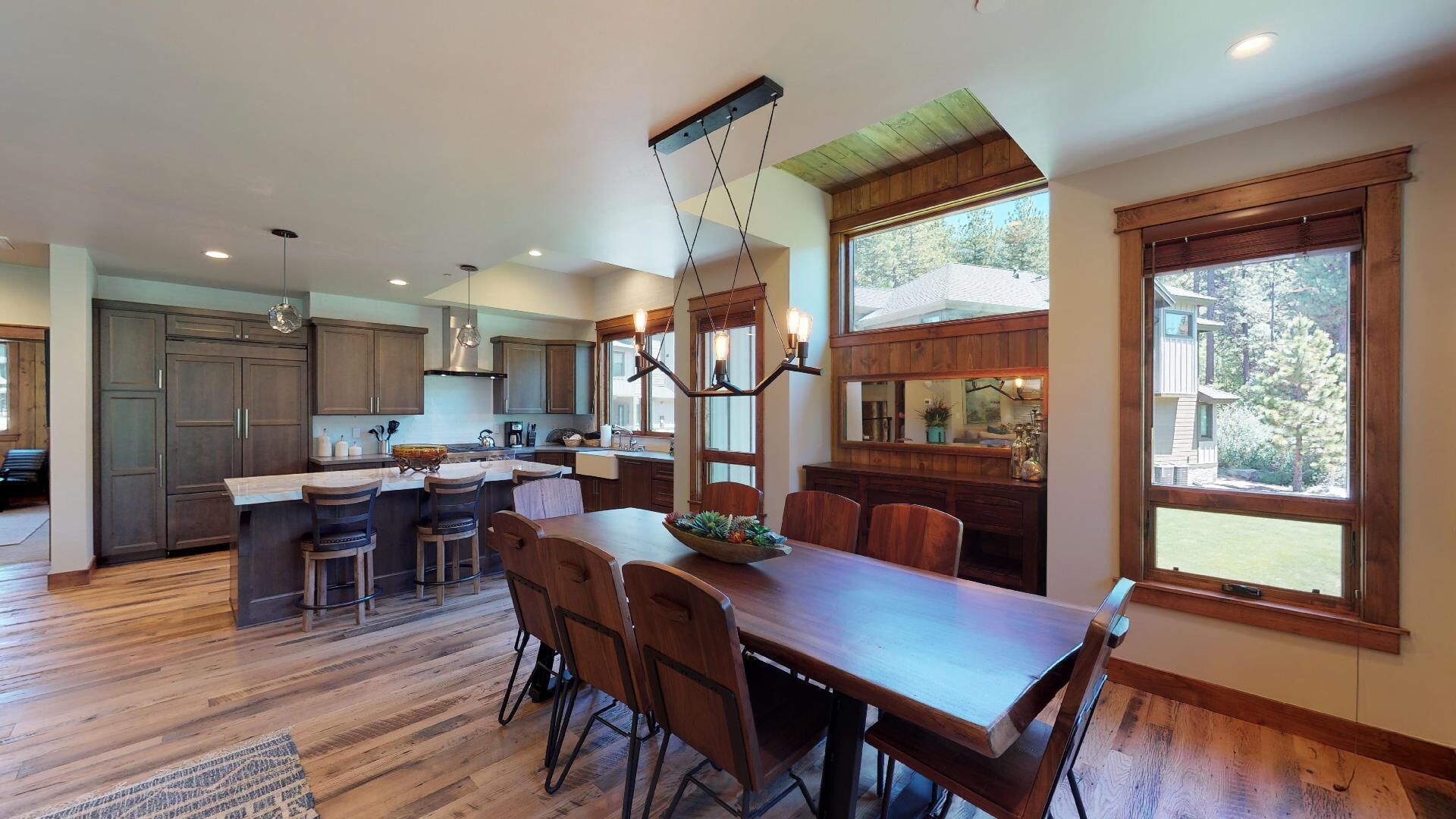 A spacious kitchen with a large island, wooden cabinets, and a dining area with a long table and chairs.