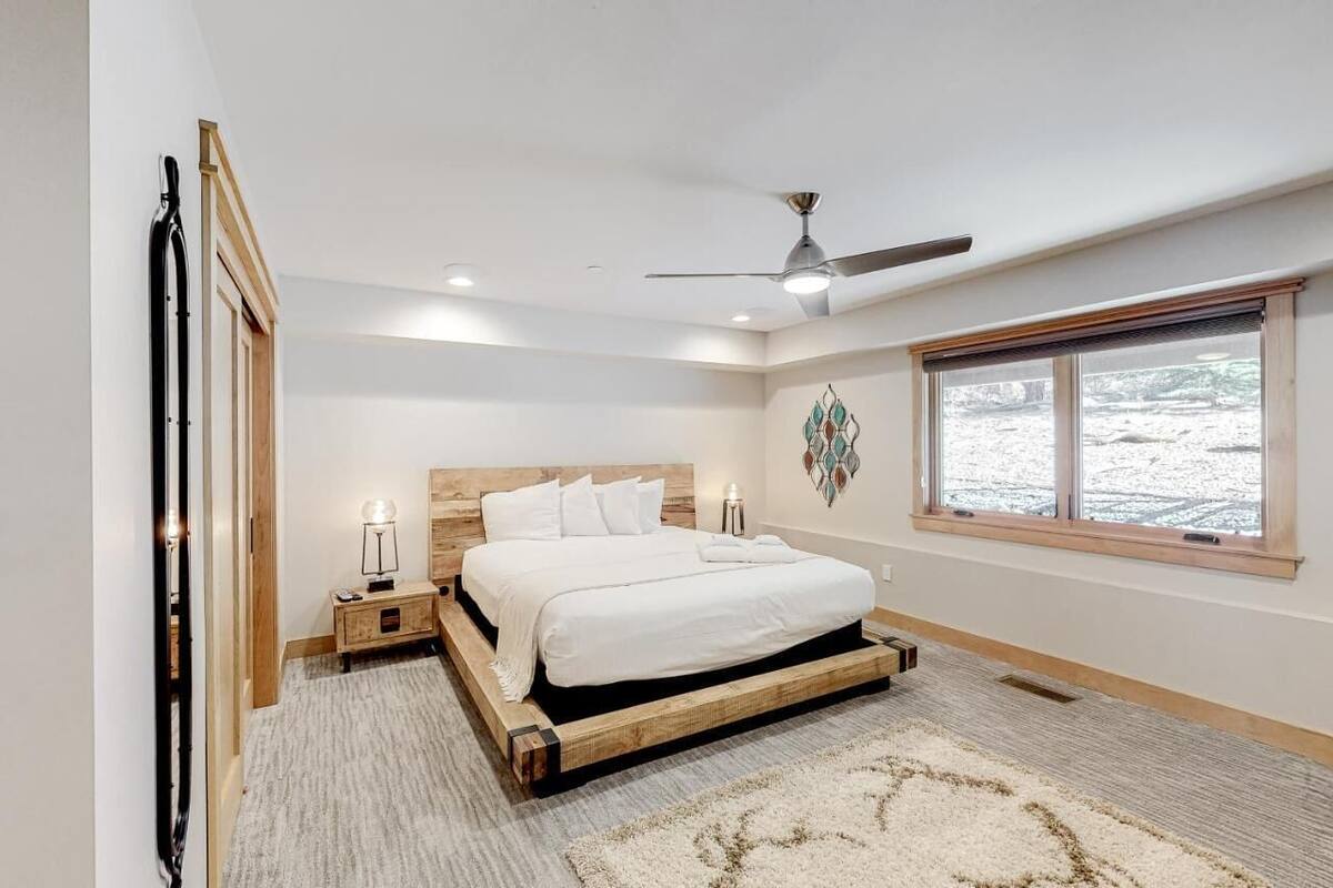 Ein Schlafzimmer mit Bett, Deckenventilator, Fenster und Nachttisch mit Lampe.