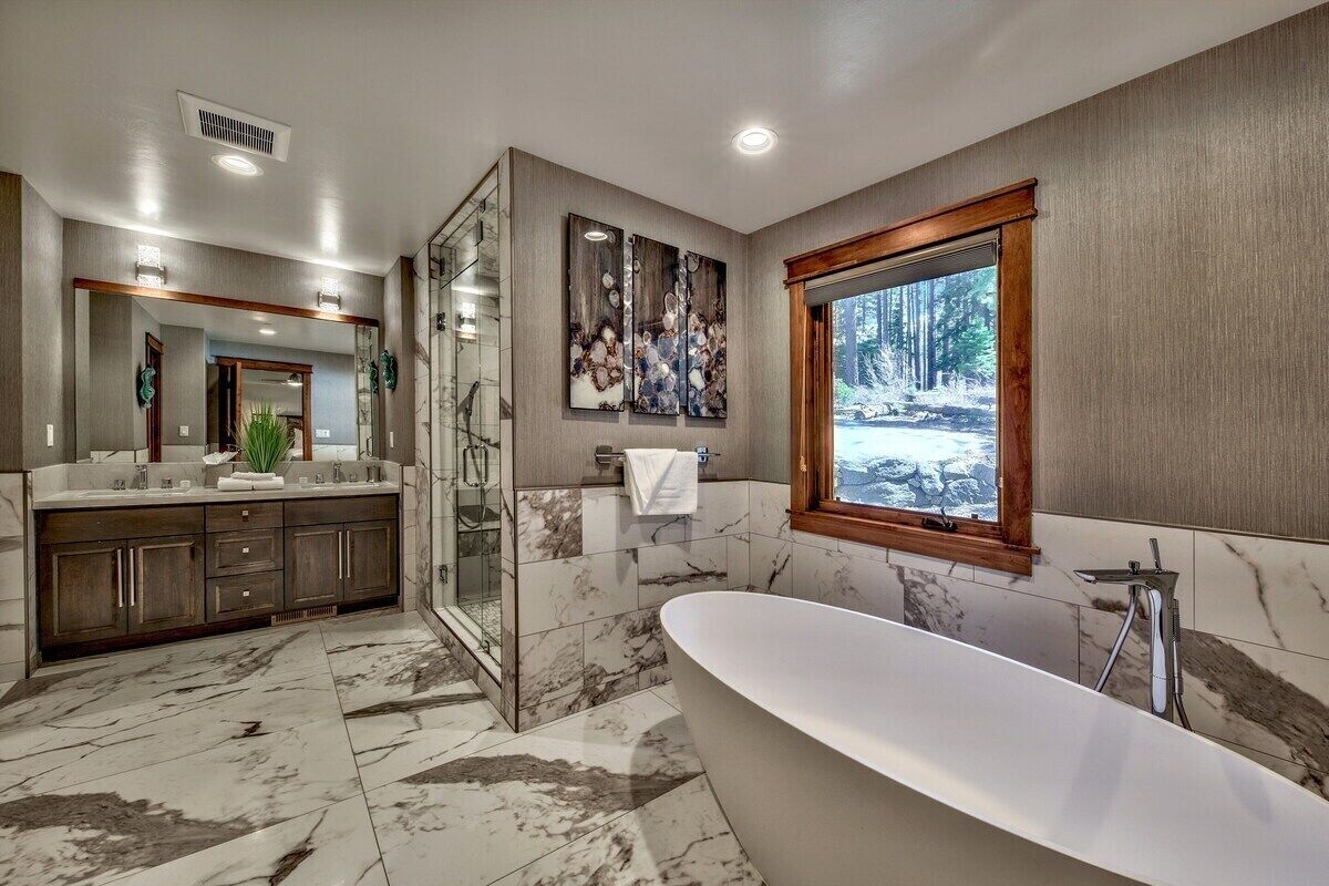 Une salle de bain moderne avec une baignoire sur pieds, une douche en verre et une grande fenêtre donnant sur un paysage enneigé.