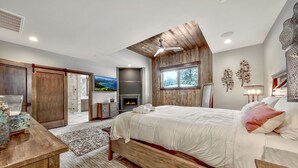 Un dormitorio moderno con una cama de madera, una chimenea y un ventanal grande.