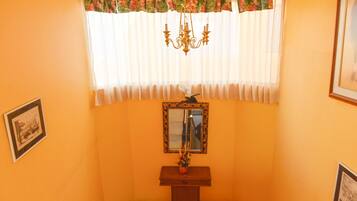 A room with a floral curtain, a chandelier, a mirror, and framed pictures on the walls.