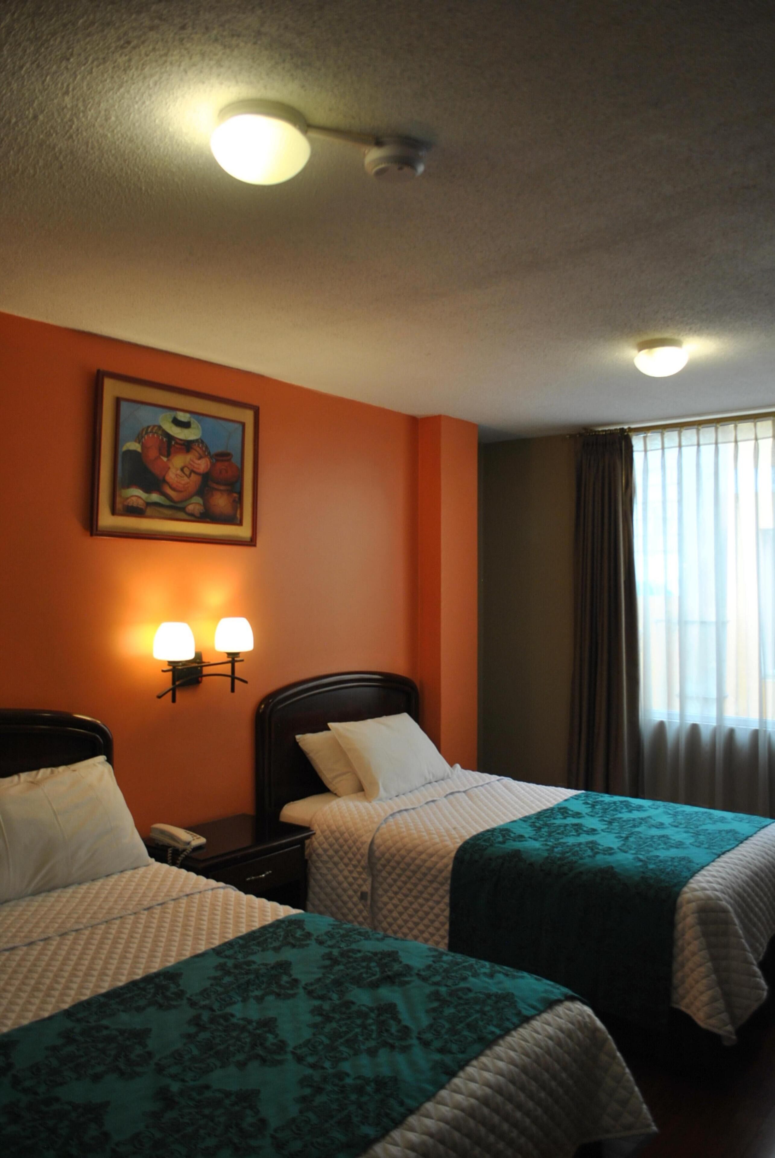 Una habitación de hotel con dos camas, un cuadro en la pared y una ventana con cortinas.