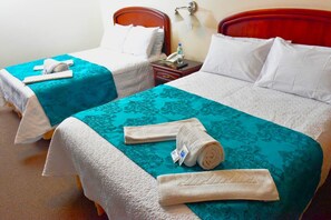 Two twin beds with teal and white bedding, a bedside table with a lamp, and a phone on the nightstand. - Hotel Makroz (Latacunga)