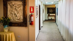 Een gang met een gekaderd kunstwerk, een brandblusser en een bordje met de aanduiding van de uitgang.