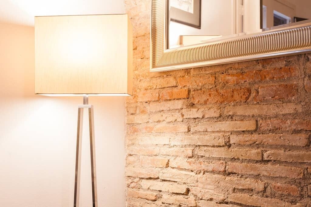 A lamp and a mirror on a brick wall.