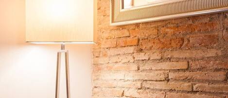 A lamp and a mirror on a brick wall.