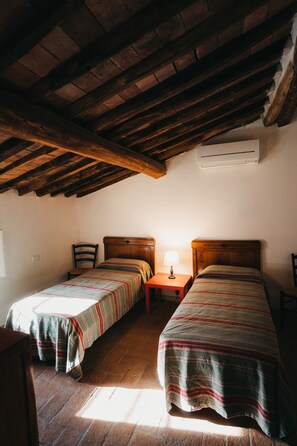 Une chambre avec deux lits, une petite table avec une lampe et un appareil de climatisation fixé au mur.