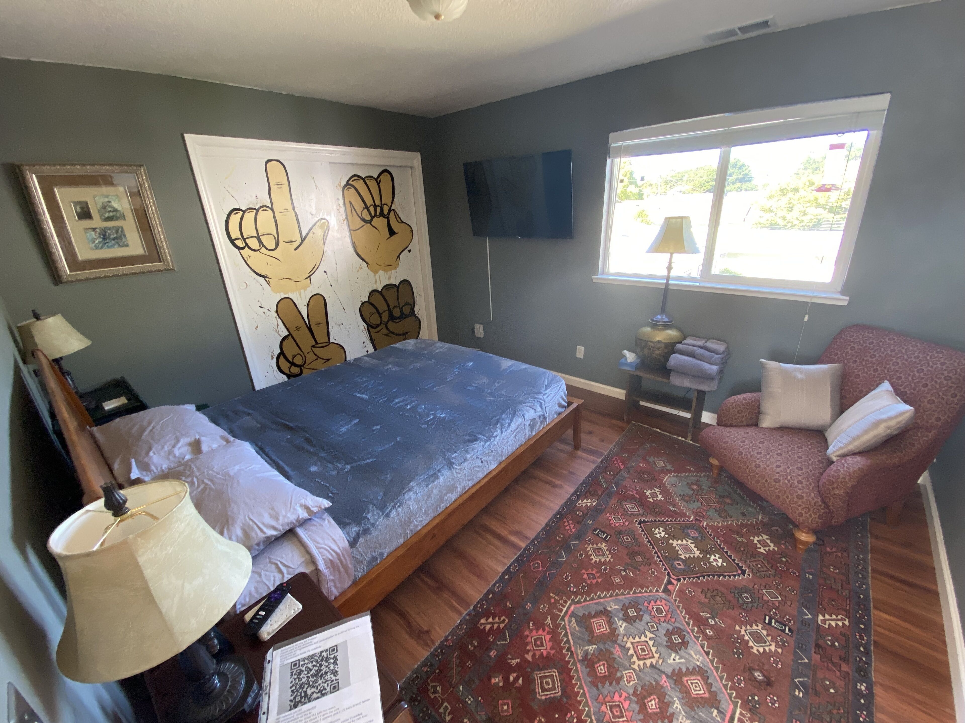 Une chambre à coucher avec un lit, une chaise, un téléviseur, une fenêtre et un tapis.