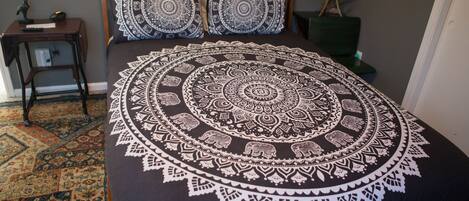 A bed with a circular patterned bedspread, a wooden headboard, and two matching pillows.