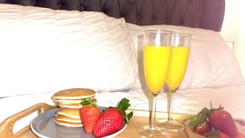 A breakfast setup with pancakes, strawberries, and two glasses of orange juice on a tray.