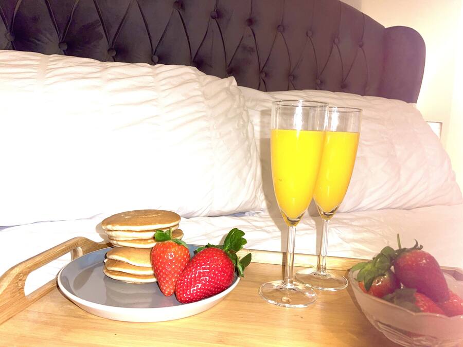 A breakfast setup with pancakes, strawberries, and two glasses of orange juice on a tray.