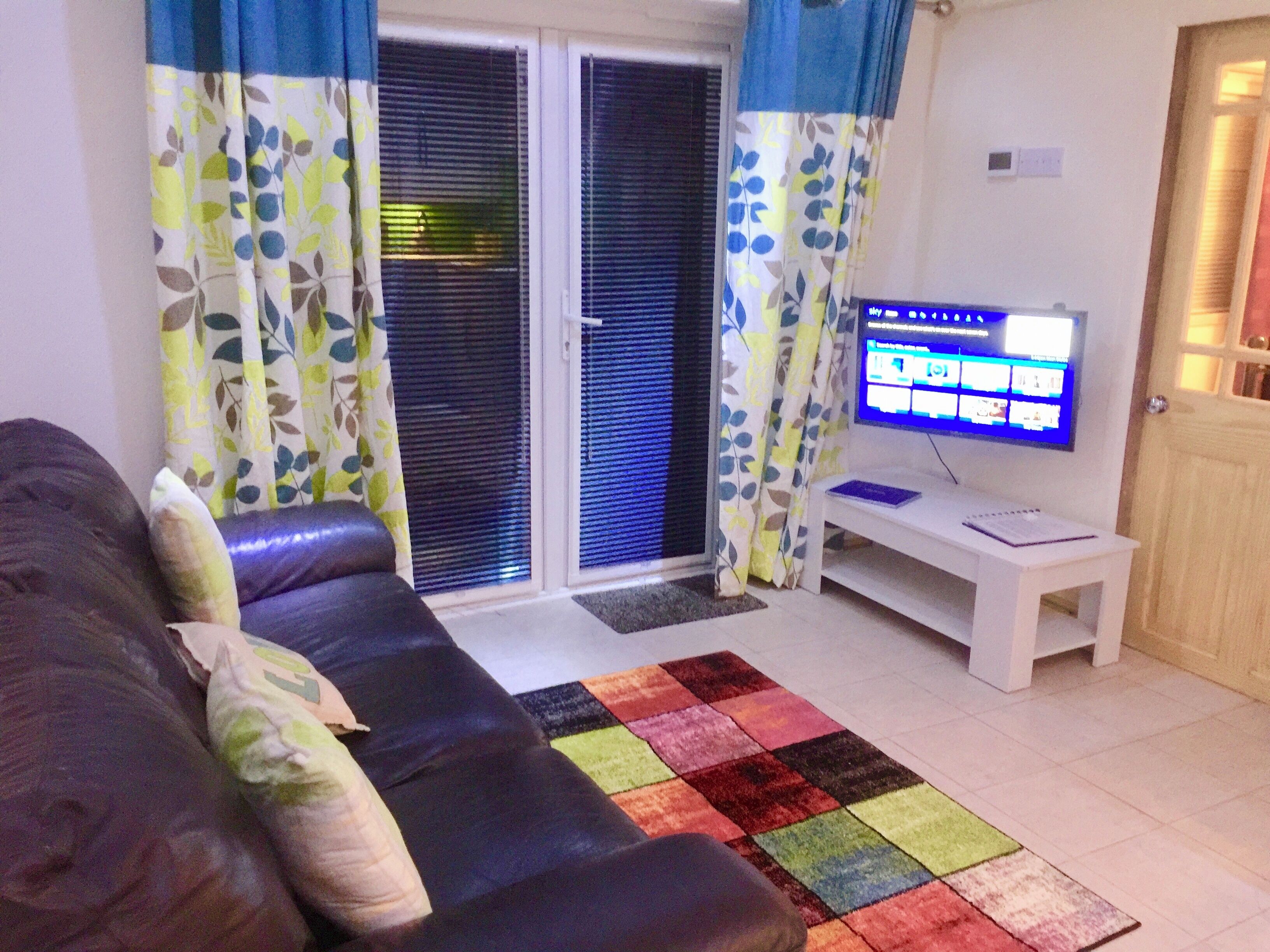 Uma sala de estar com um sofá, uma televisão e um tapete estampado.