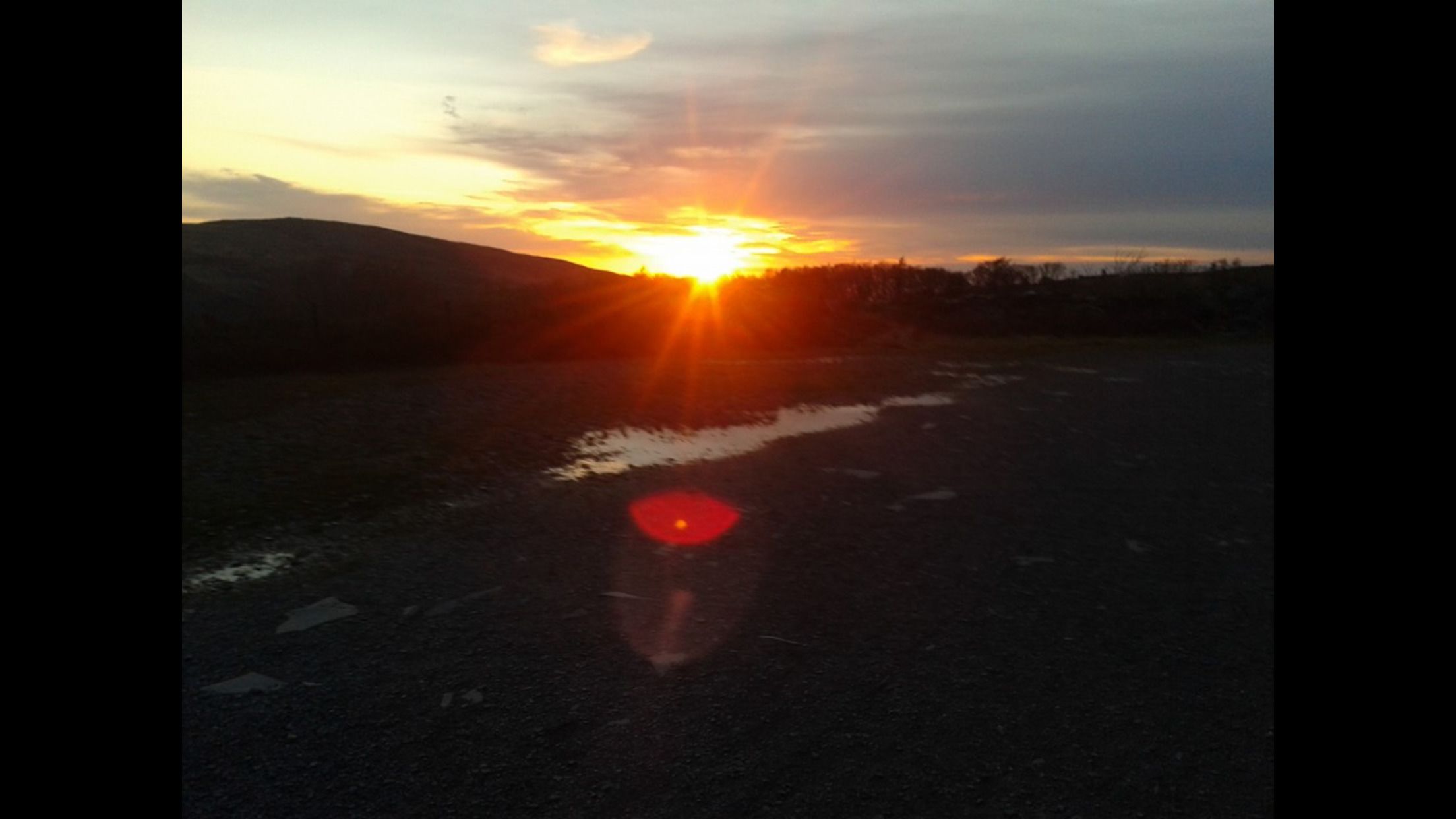 Un atardecer sobre una llanura extensa con una carretera en primer plano.