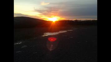 Un atardecer sobre una llanura extensa con una carretera en primer plano.