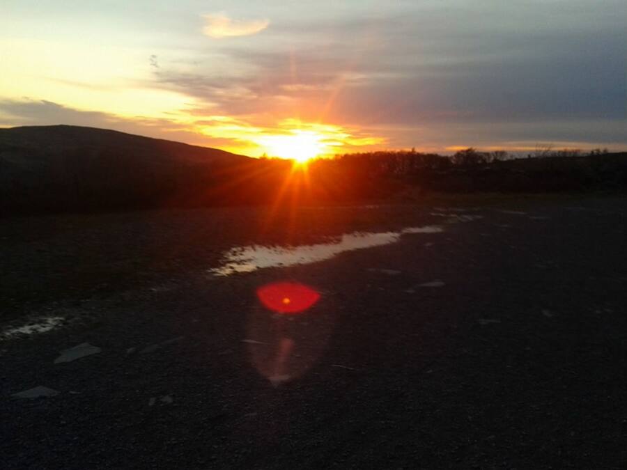 Tramonto su un paesaggio piatto con una strada in primo piano.