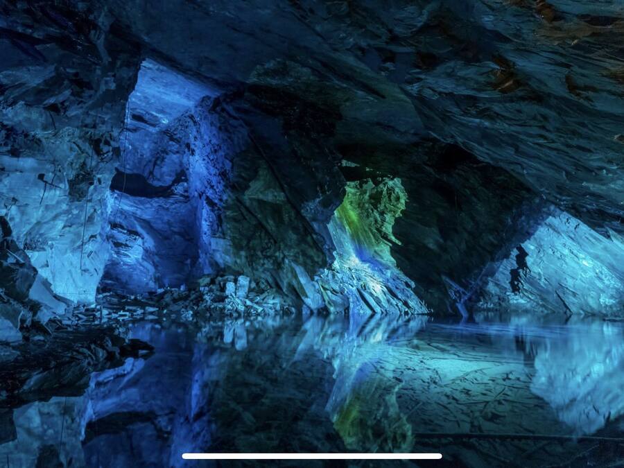 An interior view of a cave with reflective surfaces and rock formations.