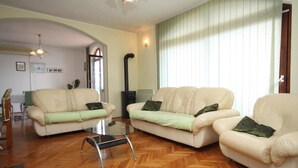 Una sala de estar con dos sofás color crema, una mesa de centro de vidrio y un piso de madera con diseño espiga.