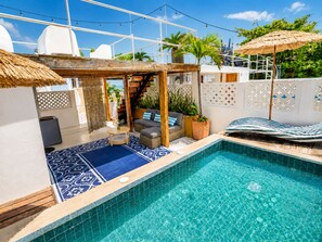 A pool area with a blue tiled floor, a seating area with a sofa and cushions, and a small table. - RentaElite Lovely 3 BR old city Cartagena w private pool (Cartagena)