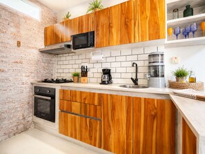Une cuisine équipée de meubles en bois, d’un four à micro-ondes, d’une machine à café et d’une bouilloire.