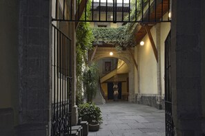 An indoor courtyard with stone flooring, a staircase, and a balcony with greenery. - Seminario 12 (Mexico City)