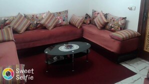 Un salon avec un canapé rouge, des coussins à rayures et une table basse en verre.