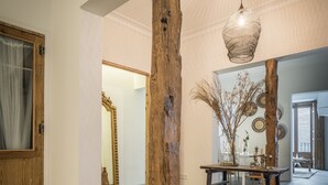 A hallway with a wooden column, a hanging light fixture, and a table with a vase. - 2 balconies 2 fireplaces WITH CHARM and SPECIAL (Madrid)