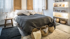 A bedroom with a large bed, wooden wardrobe, bedside tables, and a shelf with framed pictures. - 2 balconies 2 fireplaces WITH CHARM and SPECIAL (Madrid)