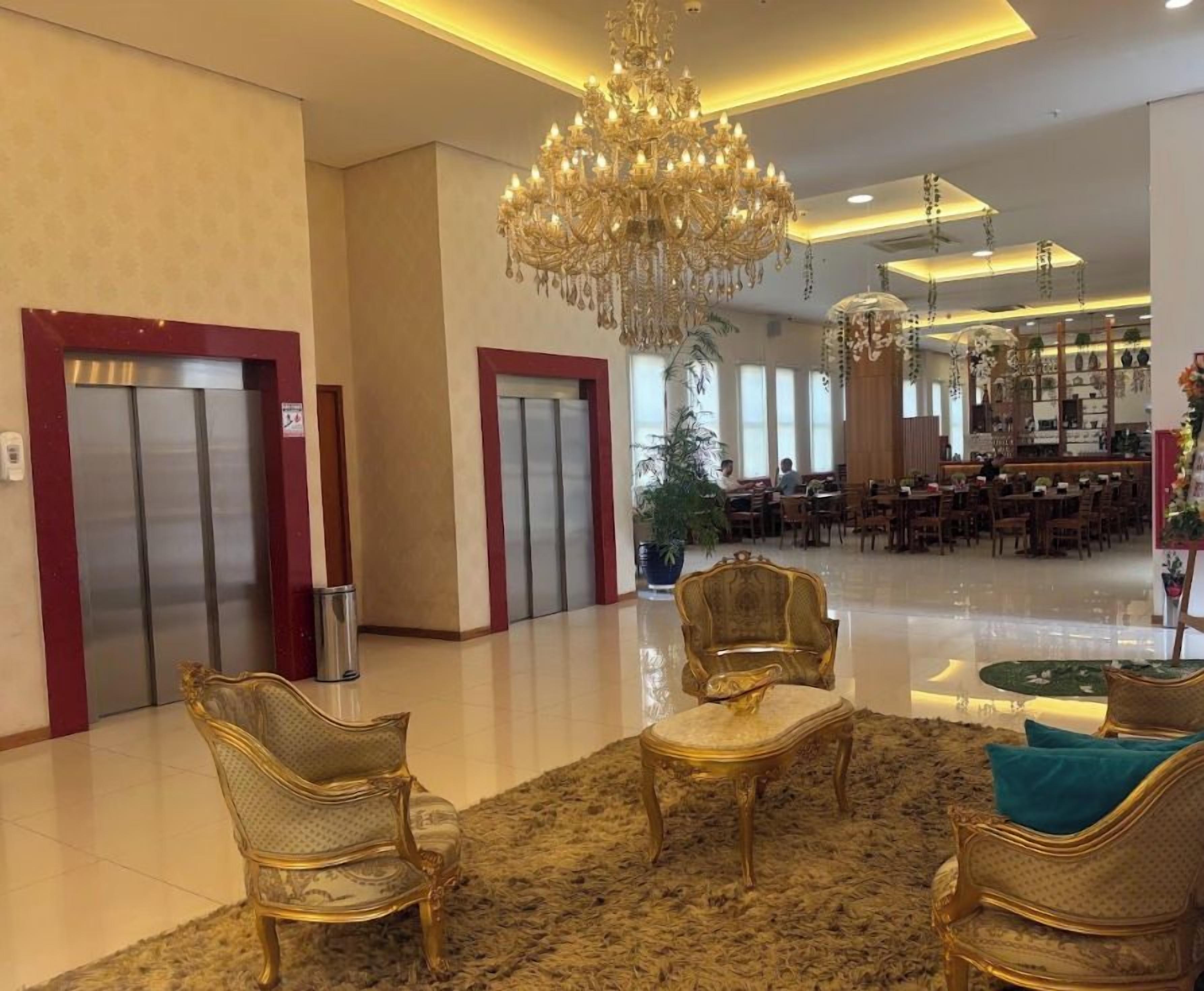 A hotel lobby with a chandelier, elevators, and seating area.