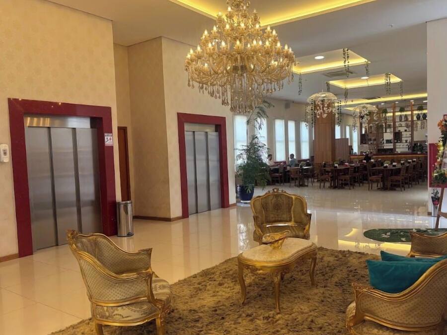 Een hotel lobby met een kroonluchter, liften en een zithoek.
