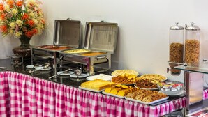 Een buffetopstelling met diverse soorten eten en een roze geruit tafelkleed.