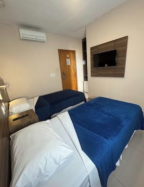 A hotel room with two beds, a TV mounted on the wall, and an air conditioning unit. - Hotel Santos Dumont Aeroporto SLZ (São Luís)