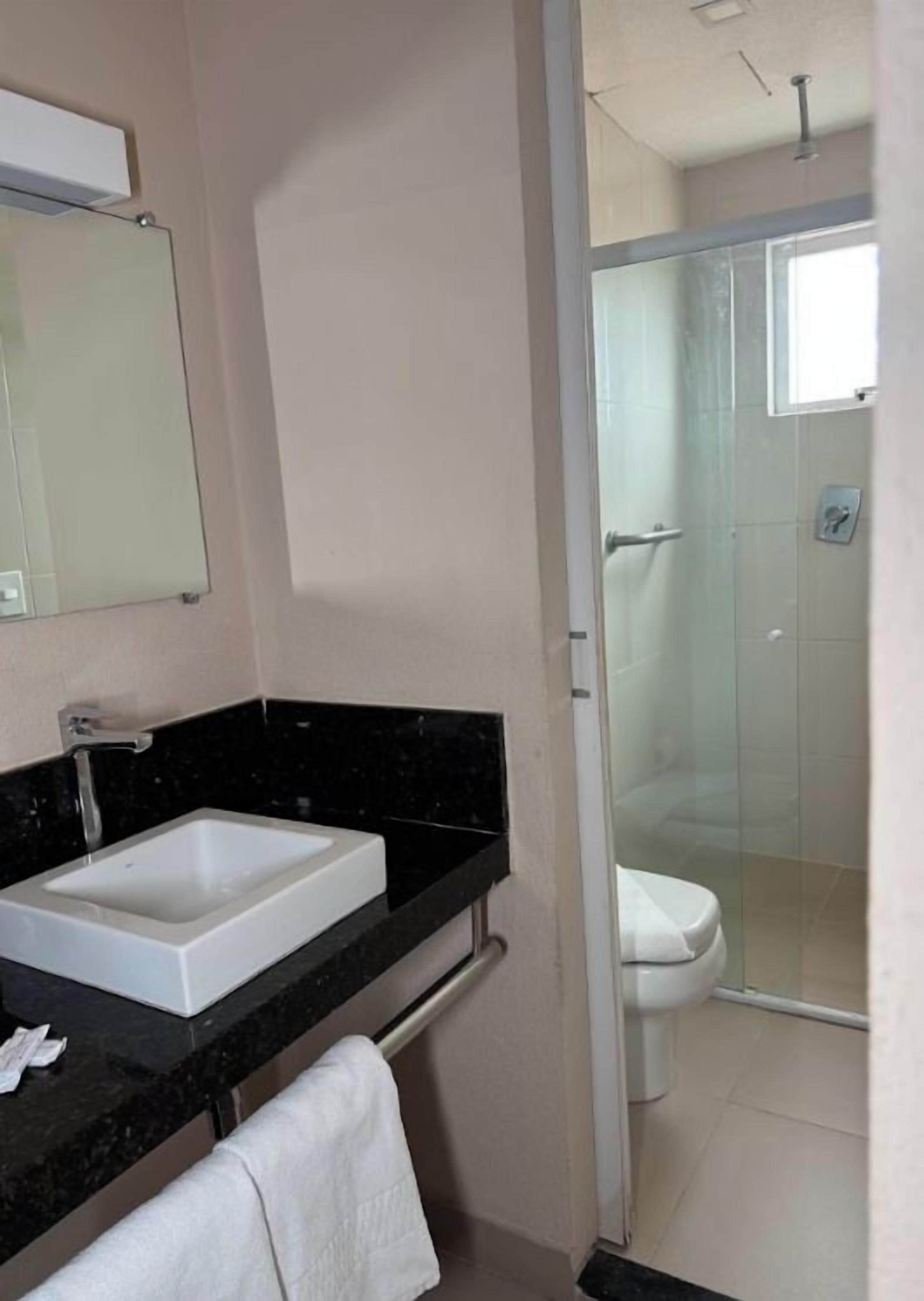 A bathroom with a white sink, a mirror, and a glass-enclosed shower area.