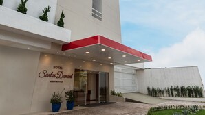 Een modern hotel met een opvallende verticale structuur, een rode overkapping en een betegeld entreegebied.