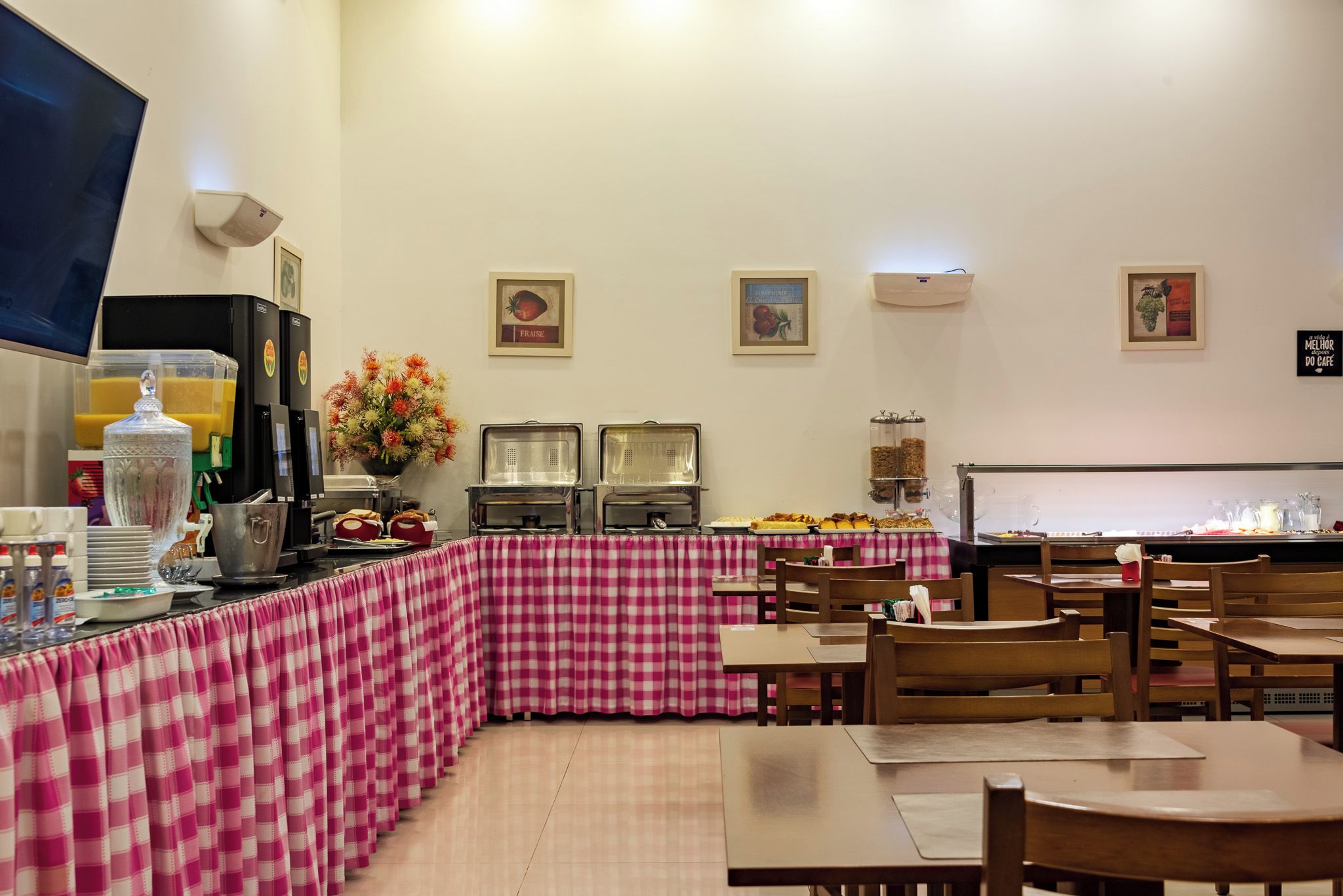 Un café con mantel a cuadros, servicio de comidas tipo buffet y una máquina de café.