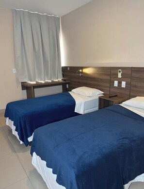 A hotel room with two beds, a wooden headboard, a bedside table, and a curtain. - Hotel Santos Dumont Aeroporto SLZ (São Luís)