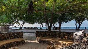 Un salón junto a la playa con paredes de piedra, muebles de madera y vistas al océano.
