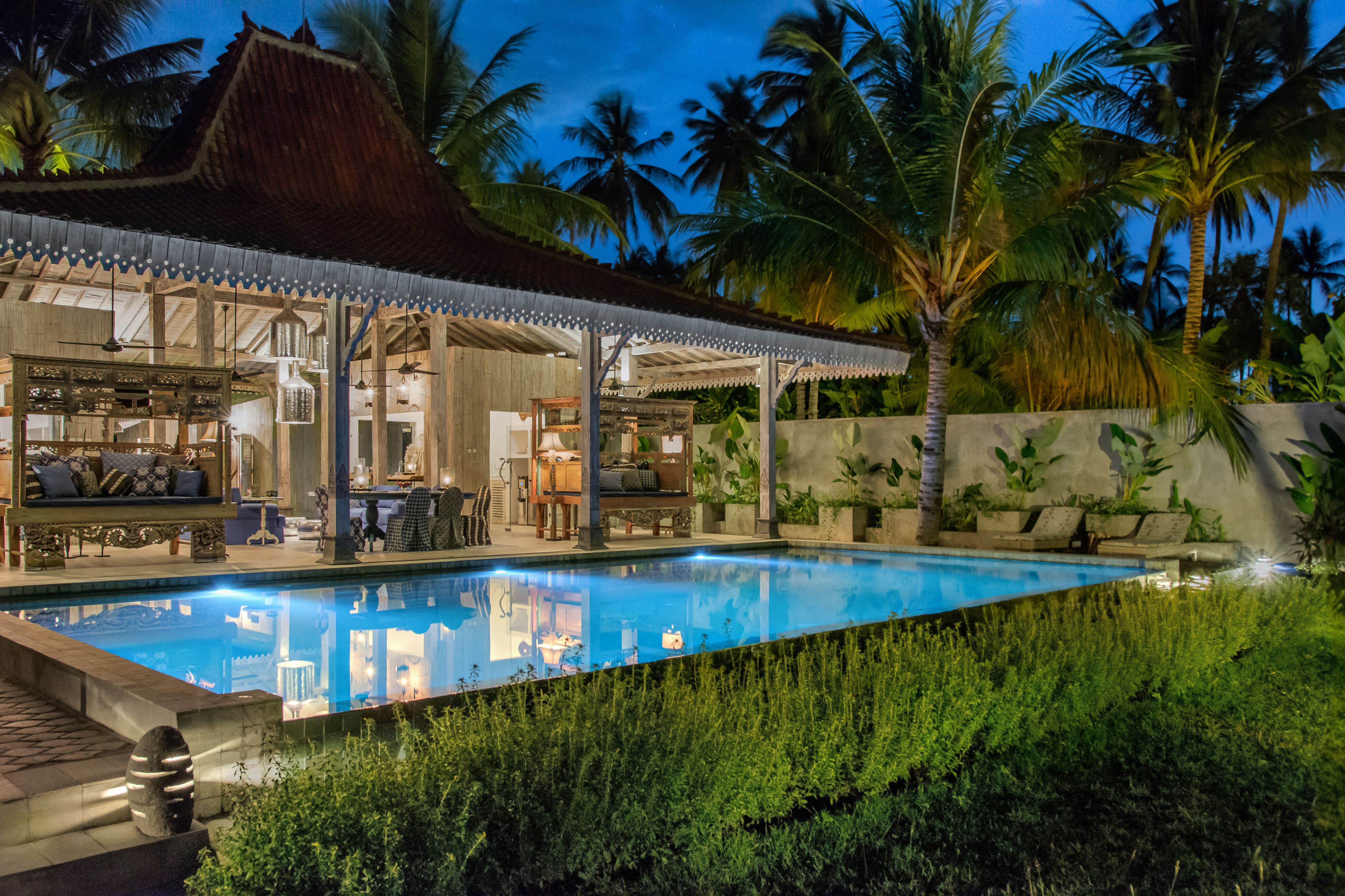 A poolside area with a covered seating area, lounge chairs, and a pool.