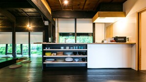 Een moderne keuken met houten balken, een inbouwkastje met servies en uitzicht op groen.
