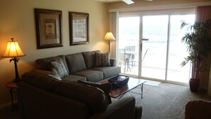 A living room with a sofa, two lamps, a ceiling fan, and a view through a sliding glass door. - Condo 331 Parkview Bay, Osage Beach Super Nice Lakefront Condo (Osage Beach)