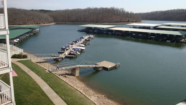 A marina with docks and boats, a bridge, and a building with a green roof. - Condo 331 Parkview Bay, Osage Beach Super Nice Lakefront Condo (Osage Beach)