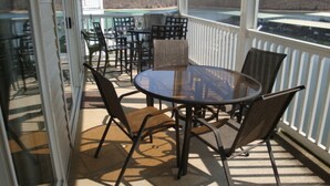 A covered outdoor seating area with a round table and chairs, overlooking a body of water and a distant shoreline. - Condo 331 Parkview Bay, Osage Beach Super Nice Lakefront Condo (Osage Beach)