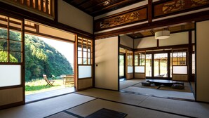 A traditional Japanese room with tatami flooring, sliding doors, and a view of a forested hillside. - Setouchi Cominca Stays Hiroshima FROSEN (Shobara)