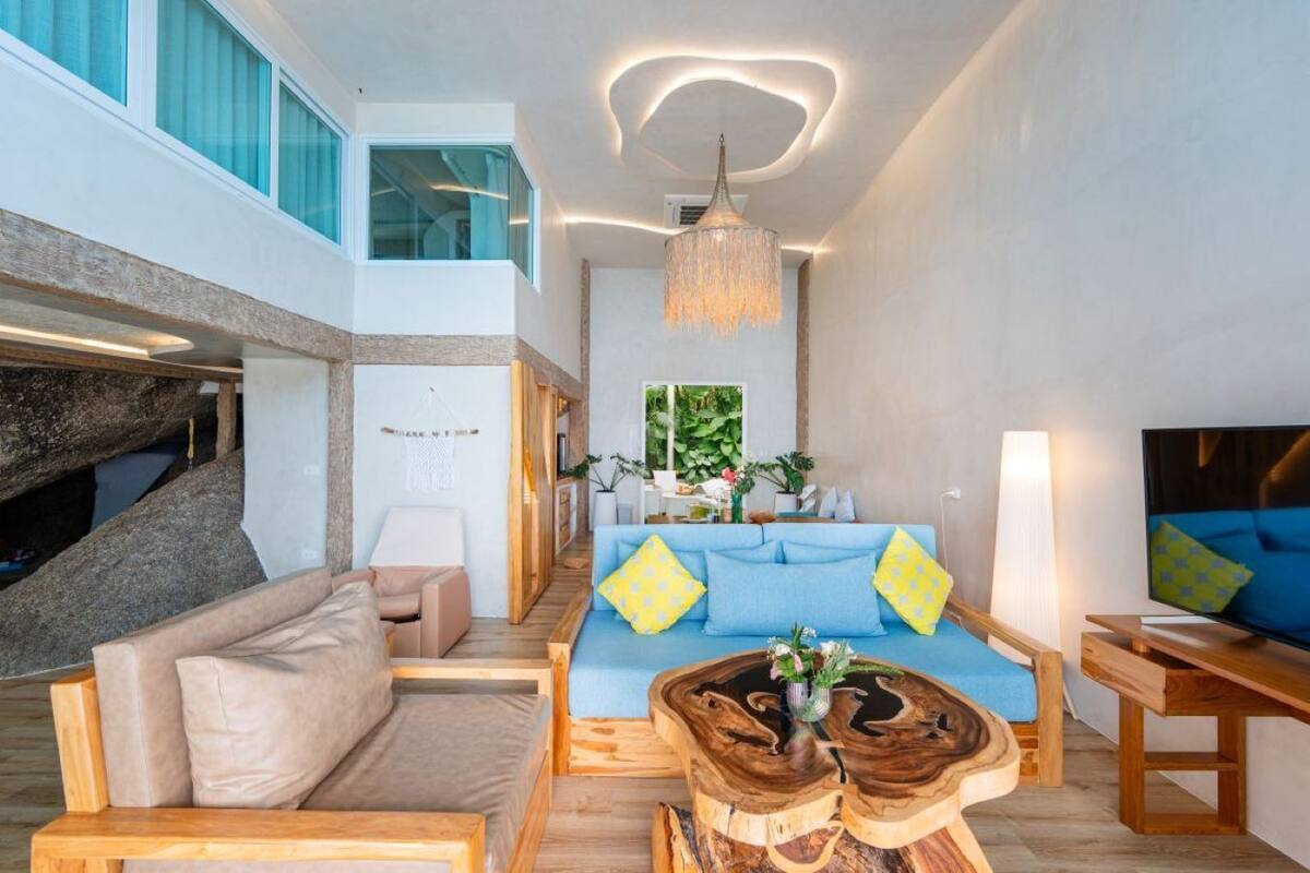 Un salon moderne avec un canapé bleu, une table basse en bois et un lustre suspendu.